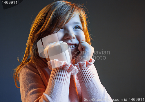 Image of The happy teen girl standing and smiling against dark blue background.