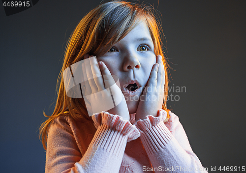 Image of The young attractive teen girl looking suprised isolated on dark blue