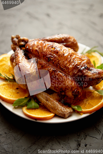Image of Roasted whole chicken or turkey served in white ceramic plate with oranges