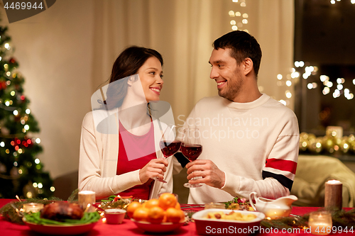 Image of happy couple drinking red wine at christmas dinner
