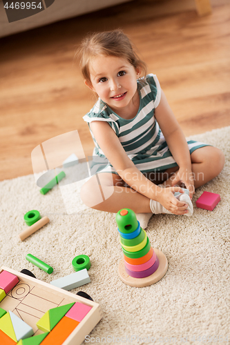 Image of happy baby girl playing with toy blocks at home