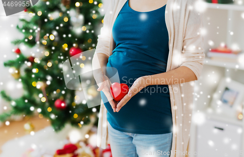 Image of close up of pregnant woman with heart at christmas