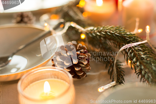 Image of pine cone and candles burning on christmas table