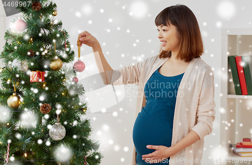 Image of pregnant woman decorating christmas tree at home