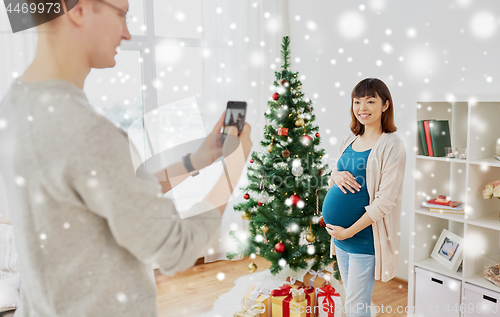 Image of husband photographing pregnant fife at christmas