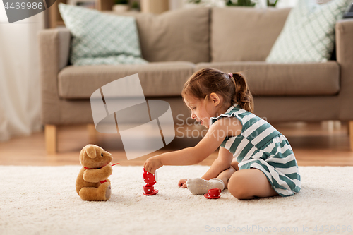 Image of little girl playing with toy tea set at home