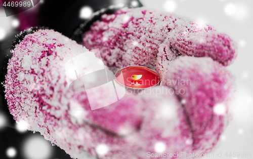 Image of close up of hands in winter mittens holding candle