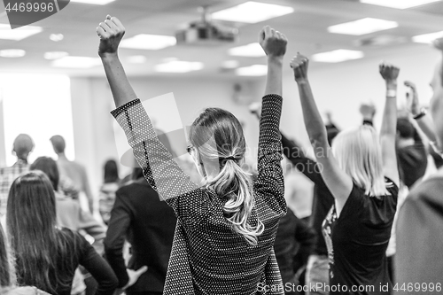 Image of Participants of interactive motivational speech feeling empowered and motivated, hands raised high in the air.