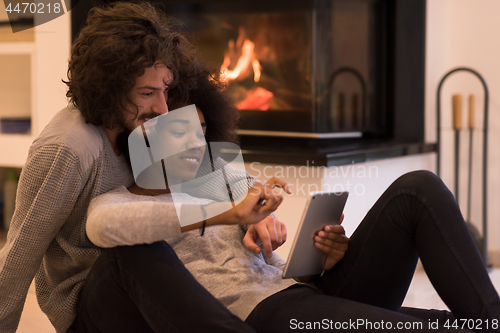 Image of multiethnic couple using tablet computer on the floor