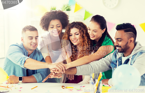 Image of happy team at office party holding hands together