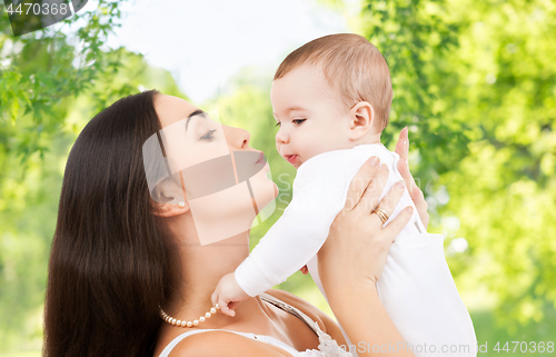 Image of mother kissing baby over green natural background