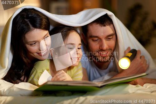 Image of happy family reading book in bed at night at home