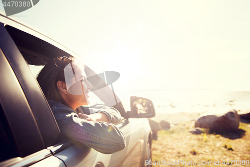 Image of happy teenage girl or young woman in car