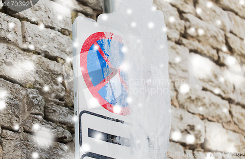 Image of ice-covered no stopping road sign over wall