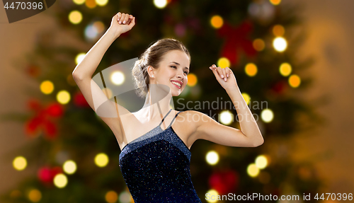 Image of smiling woman dancing with raised hands