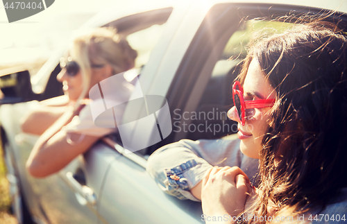 Image of happy teenage girls or women in car at seaside