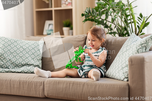 Image of happy baby girl playing with toy dinosaur at home
