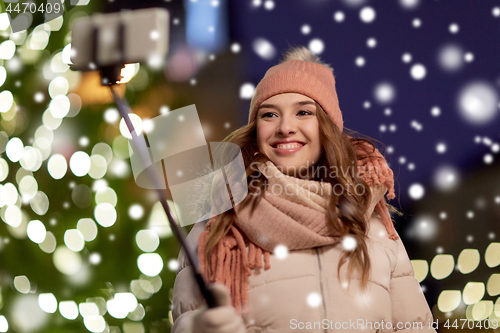 Image of young woman taking selfie over christmas tree