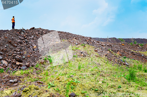 Image of The worker is at the top of the rock heap in his quarry