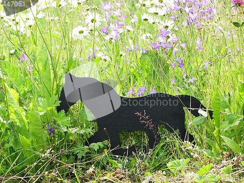 Image of Black wooden horse among flowers