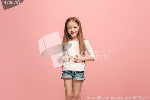 Image of The happy teen girl standing and smiling against pink background.