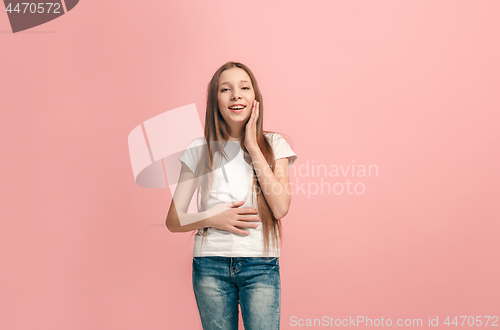 Image of The happy teen girl standing and smiling against pink background.