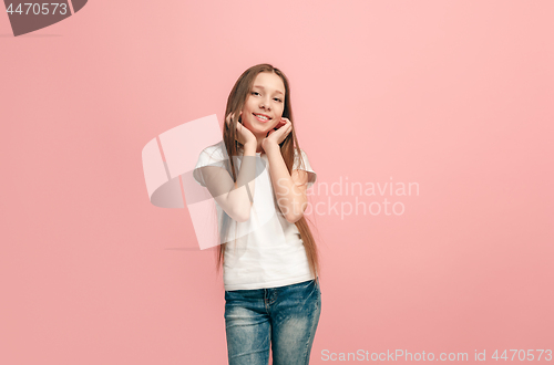 Image of The happy teen girl standing and smiling against pink background.