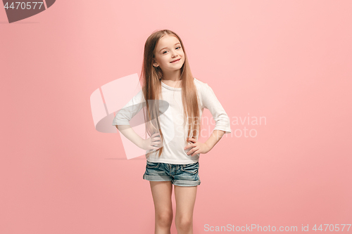 Image of The happy teen girl standing and smiling against pink background.