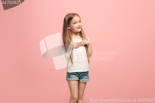 Image of The happy teen girl standing and smiling against pink background.