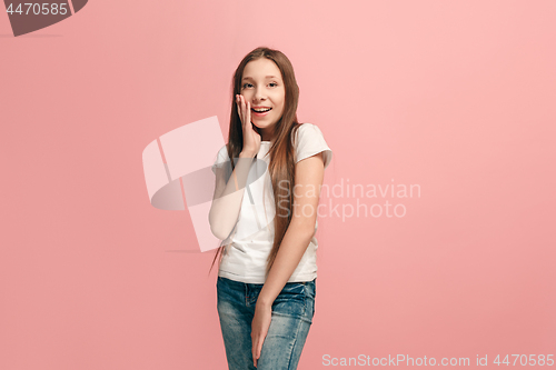 Image of The young teen girl whispering a secret behind her hand over pink background