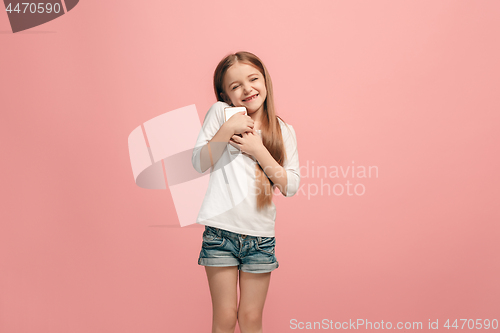 Image of The happy teen girl standing and smiling against pink background.