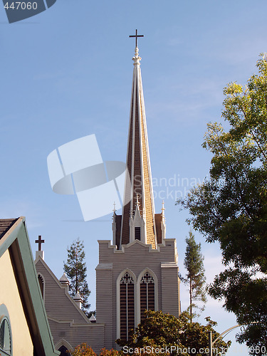 Image of Christian church steeple with blue sky and tree