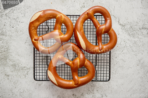 Image of Three german fresh baked pretzel buns placed on steel grill frame