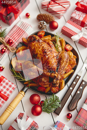 Image of Roasted whole chicken or turkey served in iron pan with Christmas decoration