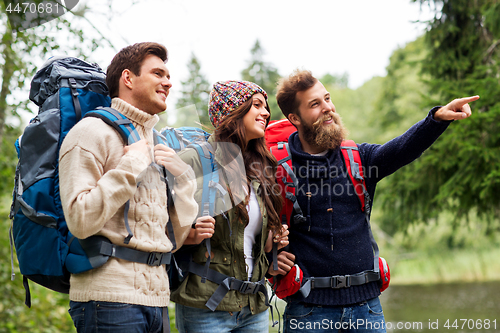 Image of happy friends or travelers with backpacks hiking