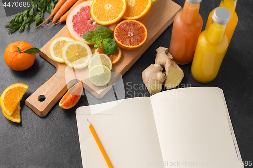 Image of close up of fruits, juices and notebook on table