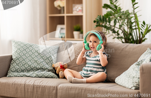 Image of redhead baby girl in headphones listening to music