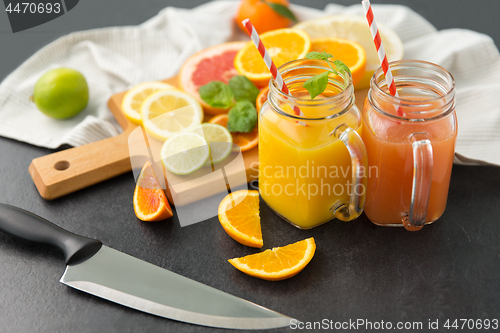 Image of mason jar glasses with juice and fruits on table