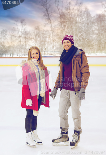 Image of happy couple holding hands on outdoor skating rink