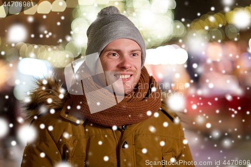 Image of happy young man over christmas lights in winter