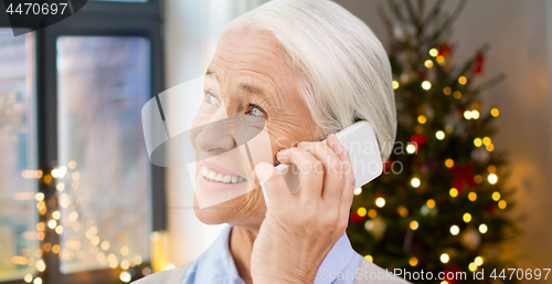 Image of senior woman with smartphone calling at home