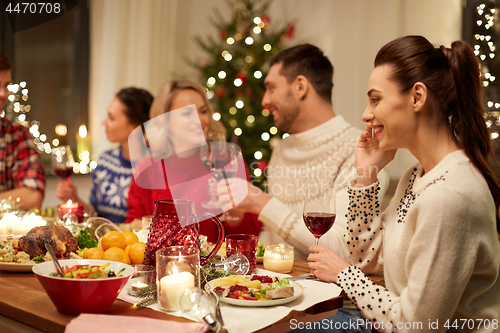 Image of happy friends having christmas dinner at home