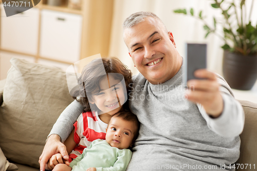 Image of happy father with sons taking selfie at home