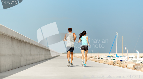 Image of couple in sports clothes running outdoors