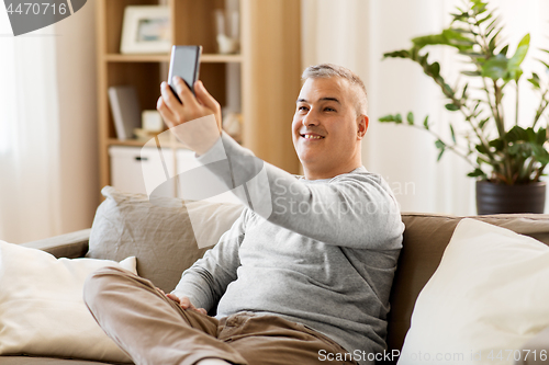 Image of man taking selfie by smartphone at home
