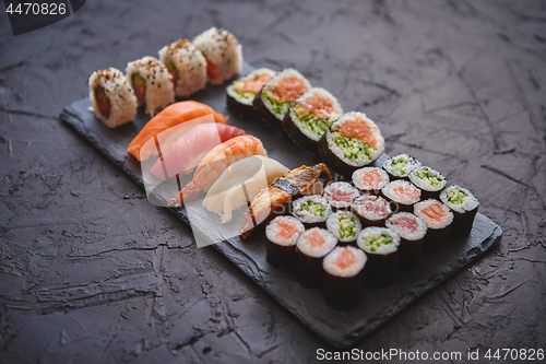 Image of Sushi rolls set with salmon and tuna fish served on black stone board