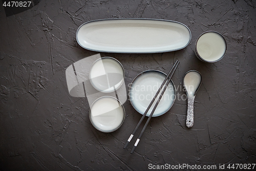 Image of Set of empty ceramic dishes for sushi and rolls on a black stone table
