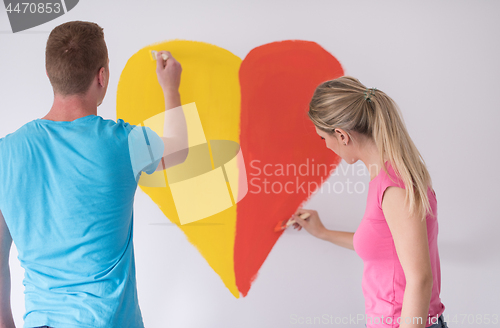 Image of couple are painting a heart on the wall