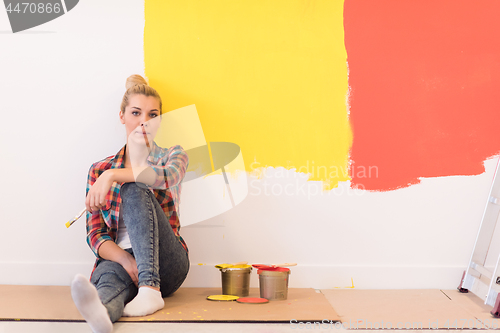 Image of young female painter sitting on floor