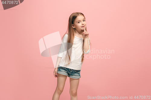 Image of The young teen girl whispering a secret behind her hand over pink background